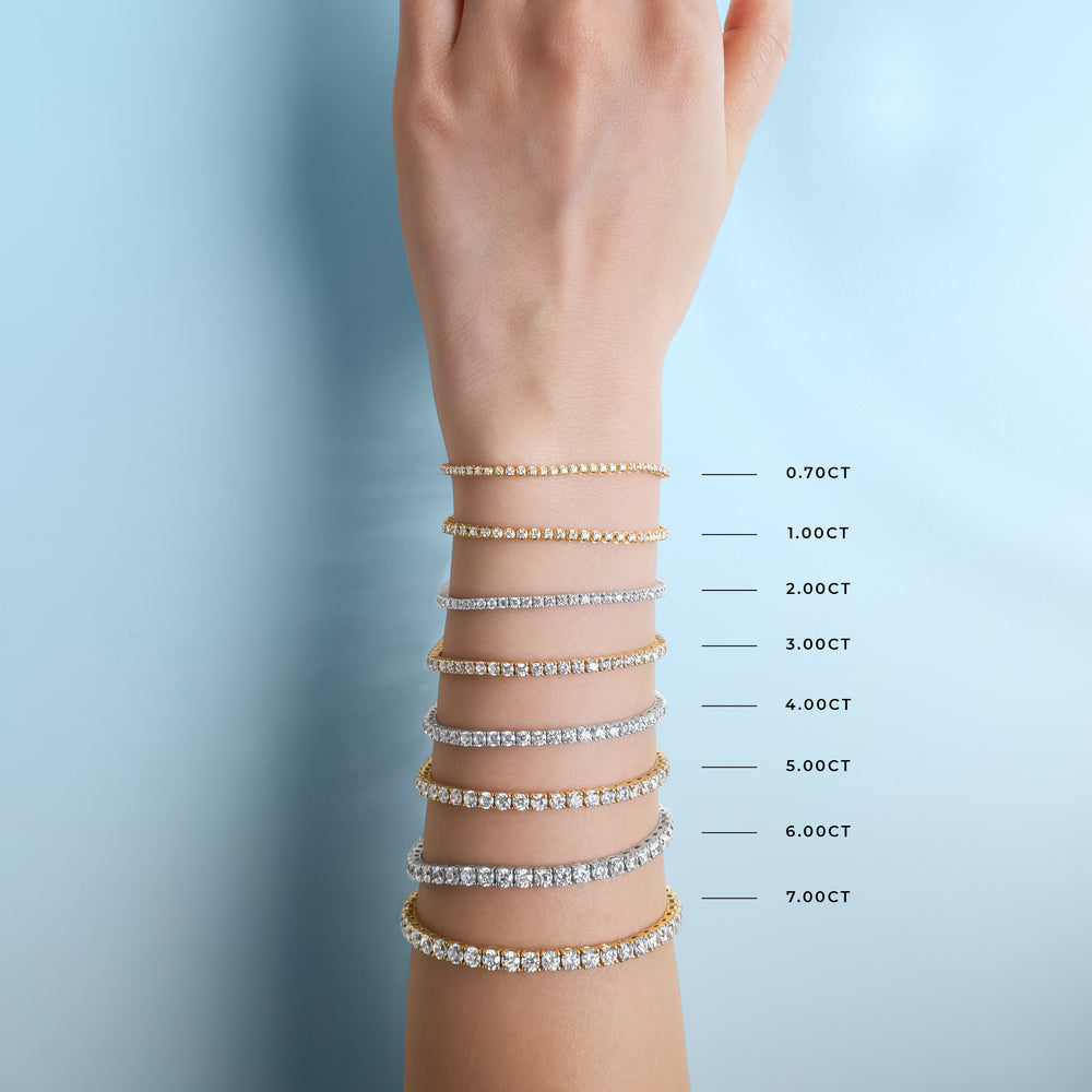Stack of lab-grown diamond tennis bracelets on a wrist with weight measurement labels against a light blue background