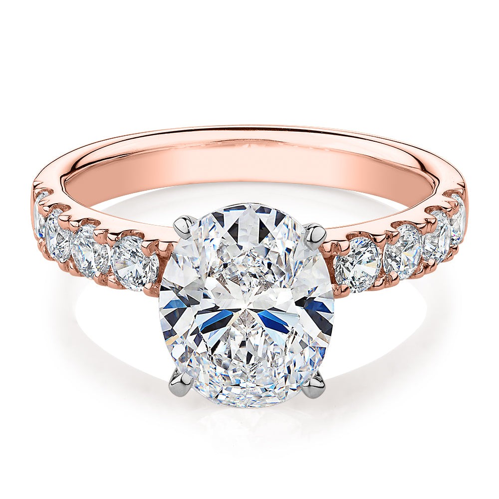 Oval shouldered engagement ring with 3.18 carats* of diamond simulants in 14 carat rose and white gold