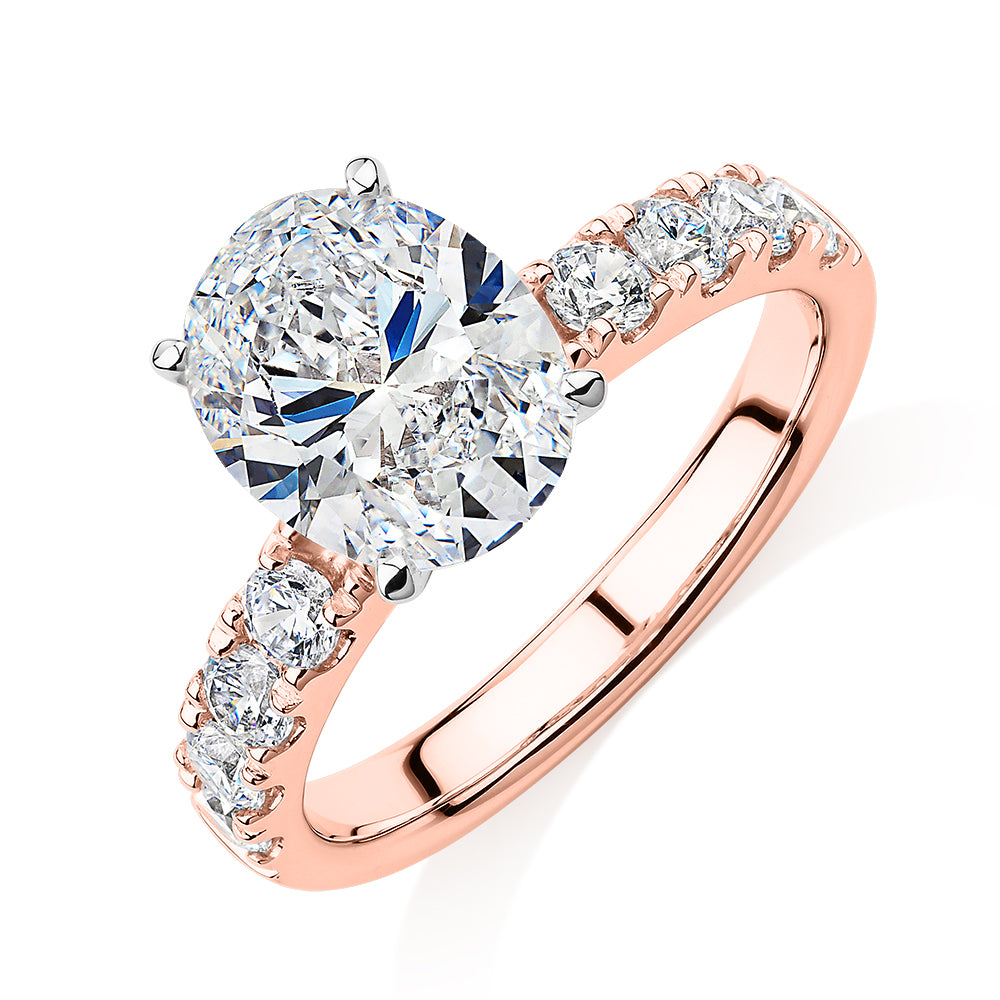 Oval shouldered engagement ring with 3.18 carats* of diamond simulants in 14 carat rose and white gold